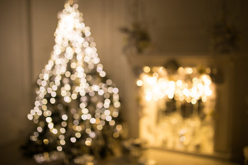 Blurred card with christmas tree and fireplace in a white room. Evening time. Christmas lights.