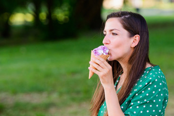 girl eating ice cream on a green background. place for an inscription. Portrait of a young urban woman with ice cream on a green background. girl eating ice cream in a green dress with white polka dot