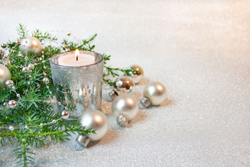 Srebrne bożonarodzeniowe tło ze świecą, bombkami i gałązkami jałowca
