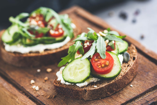 Rye Bread With Cream Cheese And Cucumber Toast Garnished With Cherry Tomato, Arugula Leaf And Seeds. Healthy Snack, Clean Eating. Closeup View, Selective Focus