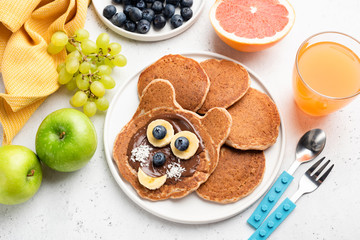Funny cat pancakes with chocolate spread and banana for kids on a plate. Baby food, pancake food art concept
