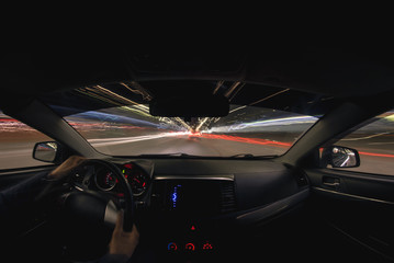 Driver is driving a car on night city road concept. Long exposure photo.