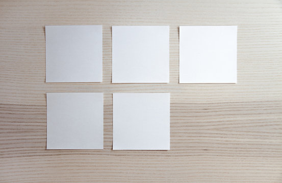 5 blank empty white sticky notes on clean wood background with free space, from top view with copy space