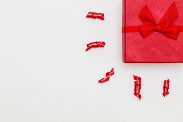 Creative Composition With Red Gift Box in Top Right Corner Against White Background. Copy Space on The Left Side