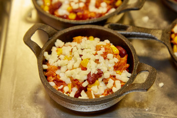 Cooking chili con carne in small pots in a restaurant.