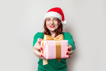 Christmas girl in santa hat with box isolated on grey background.