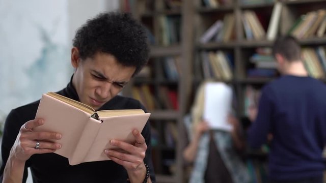 Young man in library reading book concentrated