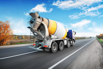 Concrete mixer truck driving fast on the countryside road against sky - 301847975