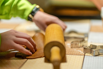 Kid in green jacket making gingerbread cookies from dough