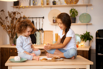 two little girls prepare Christmas cookies in the kitchen