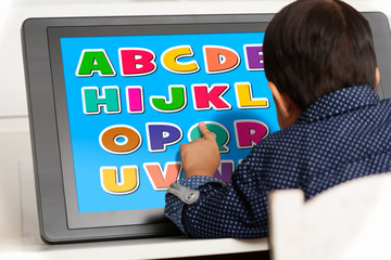 A young boy using a touchscreen to play a learning app.
