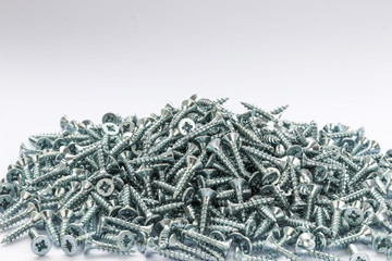 Small pile of Metal galvanized screws.  20 mm screws side view.  Fixing materials on a white background.  Isolated heap of wood screws. - obrazy, fototapety, plakaty