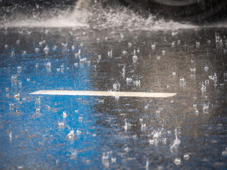 It's raining. Raindrops on a wet road. Road marking and splash from a car