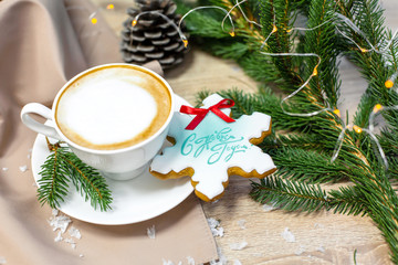 Christmas and happy new year card with cup of coffee, pine, fir branch and gingerbread on wooden table background, copy space, top view
