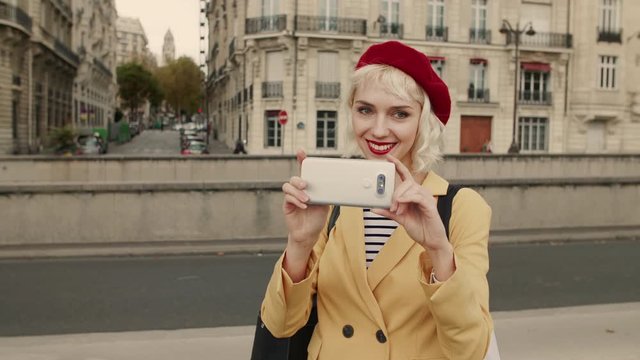 Young happy smiling fashionable traveller, lady, shooting video with smartphone