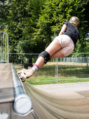 young woman in shorts skating the top of a halfpipe