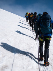 a group of alpinists is hiking as a roped party on a glacier