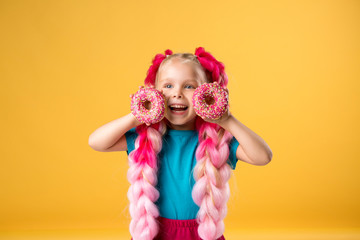 little girl with donuts on yellow background isolate, space for text