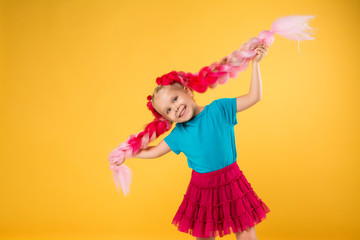 little girl with braids of pink kanekalon on a yellow background isolate