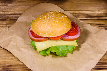Fresh hamburger on brown paper on wooden table
