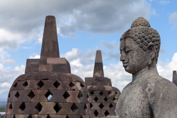 A Buddah in his stupa of Borobodur overlooking the surrounding land and watching over the volcanoes. Some of them are opened during dry season. A stunning monument in Central Java, Indonesia.