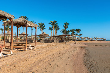Beach with straw umbrellas and sunbeds. Egyptian resort in Sharm el Sheikh. Vacation concept.