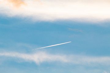 Nuvem brancas e um rastro de avião  com o céu azul de fundo