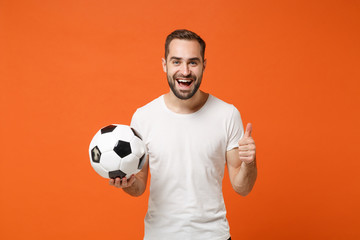 Fototapeta Smiling young man in casual white t-shirt posing isolated on bright orange background studio portrait. People sincere emotions lifestyle concept. Mock up copy space. Hold soccer ball showing thumb up. obraz