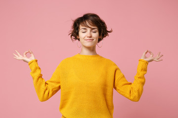 Young brunette woman girl in yellow sweater posing isolated on pastel pink background. People...