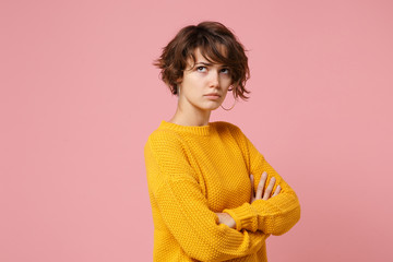 Offended pensive young brunette woman girl in yellow sweater posing isolated on pastel pink...