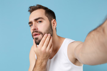 Close up shot bearded young man 20s years old in white shirt doing selfie isolated on blue pastel wall background, studio portrait. Skin care healthcare cosmetic procedures concept. Mock up copy space