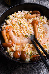 spicy instant noodles soup with shrimps ans mushrooms. served by chopsticks. close up