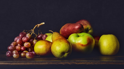 Ripe fruits, apples, pears grapes on a wooden old table and dark background. Fruit still life