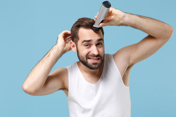 Close up bearded young man 20s years old in white shirt hold electric razor isolated on blue pastel...
