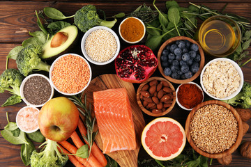 Healthy food clean eating selection: fish, fruit, vegetable, cereal, leaf vegetable on rustic background