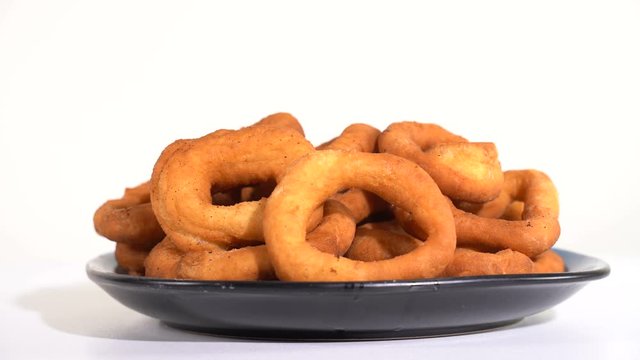 A lot of fresh fried doughnuts in a plate on the table spinning in front of the camera