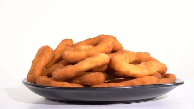 A lot of fresh fried doughnuts in a plate on the table spinning in front of the camera
