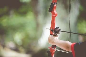 Closeup shot of a person holding a bow and arrow with a blurred background