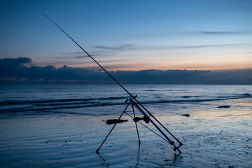 Fototapeta na wymiar Beautiful sunset at low tide and fishing rod ready for night fishing at low tide in Bognor Regis.