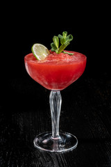 Strawberry daiquiri cocktail with lime, strawberry syrop, cherry and mint on black background.