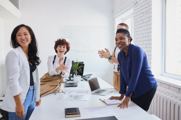 Multiethnic team of happy people applauding at international conference after successful solution