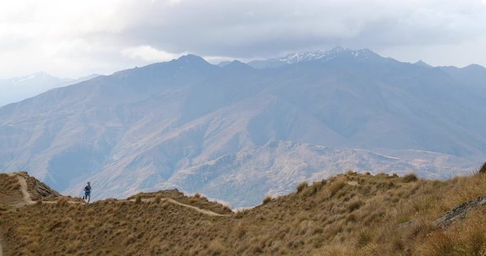 Running man atlete on trail run in mountains. Fit male runner exercising jogging and cross country running in amazing beautiful mountain nature landscape. 59.94 FPS SLOW MOTION.