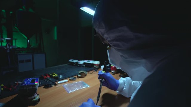 Crazy man making improvised explosive device, soldering in illegal laboratory