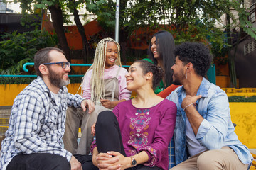Happy multiethnic girls and guys talking and chilling outside. Carefree, happiness and bonding feelings.