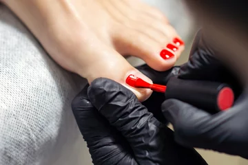 Foto auf Acrylglas Frau, die Nagelpolitur mit rotem Nagellack an den Fingern der Füße von einem professionellen Podologen aus nächster Nähe erhält. © okskukuruza