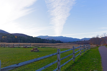 Corn field in late autumn after crop picked up. Trail along fields with distant mountains in a view, Stowe, Vermont, USA.