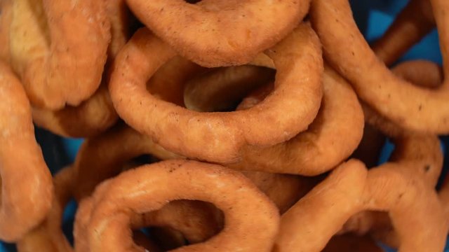 A lot of fresh fried doughnuts in a plate on the table spinning in front of the camera. Close-up