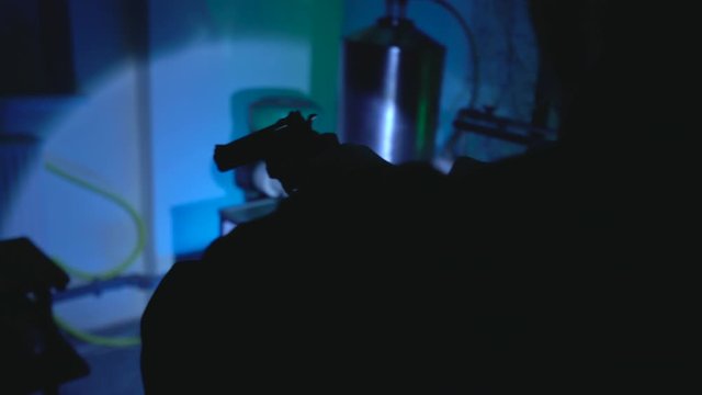 Man with handgun examining illegal laboratory, night police raid, investigation