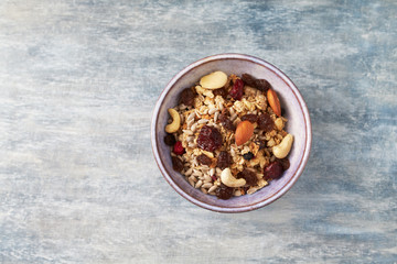 Bowl of granola with nuts and raisins. Concept for a tasty and healthy meal. Rustic wooden background. Top view. Copy space. 