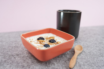  Cup of coffee, bowl with yogurt, cereals and blueberries.